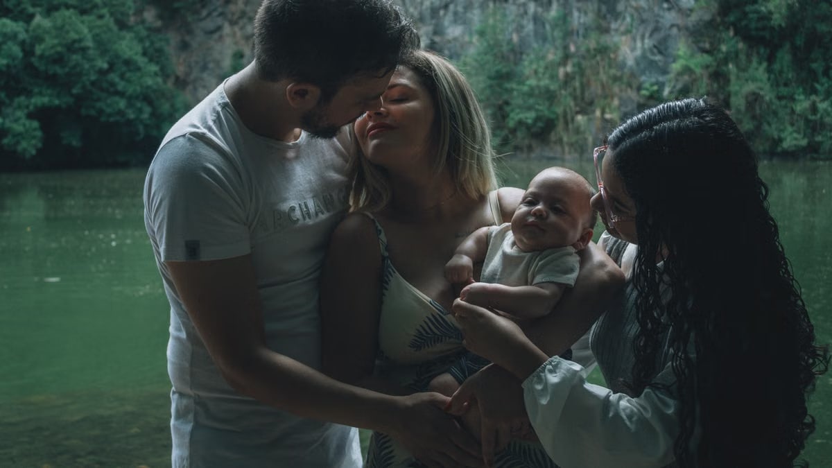 A family enjoying a tender moment together by a peaceful lake surrounded by lush greenery.